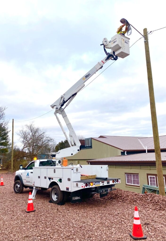 Agostino Utilities Bucket Truck With Man Raised Up Working On Light Pole